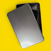 Silver phone jail tin with lid partially closed over a locked-away smartphone