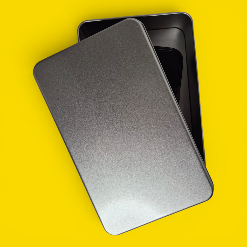 Silver phone jail tin with lid partially closed over a locked-away smartphone
